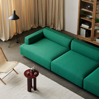 Vibrant green modular sofa with minimalist design, set against a neutral backdrop and warm curtain tones.
