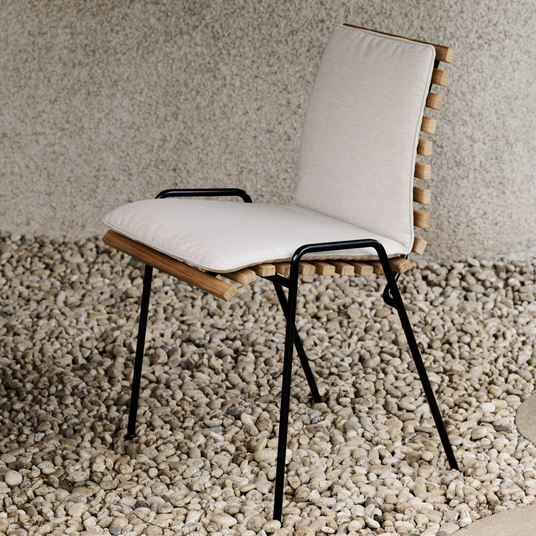 Neutral beige cushion with natural wood accents and black metal legs, set against a textured gray background.