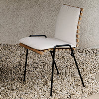 Neutral beige cushion with natural wood accents and black metal legs, set against a textured gray background.