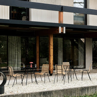 Striped wooden chairs with black metal legs, set against a neutral gravel and modern architecture backdrop.