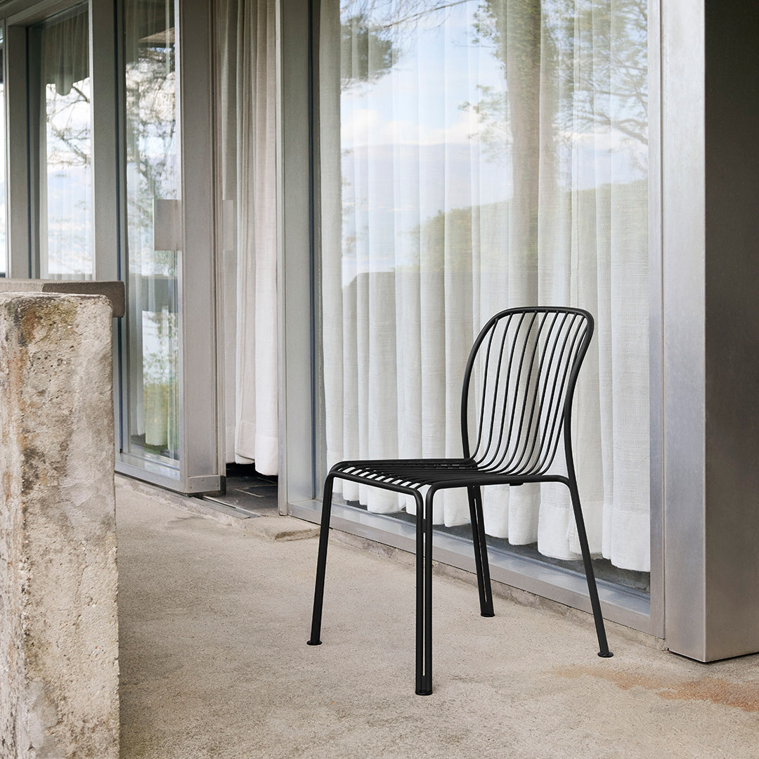 Black metal chair with a simple, minimalist striped pattern, set against a soft, neutral backdrop.