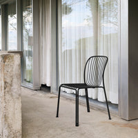 Black metal chair with a simple, minimalist striped pattern, set against a soft, neutral backdrop.