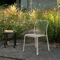 White striped chair against a natural green backdrop, complementing the soft tones of outdoor landscaping.