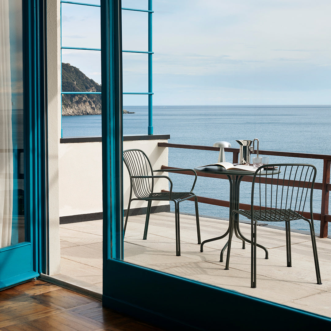 "Stylish black outdoor table and chairs with turquoise accents, set against a serene coastal view."
