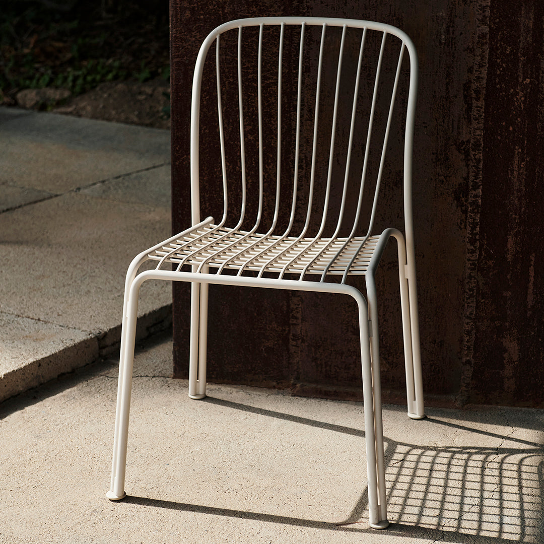 White metal chair with a minimalist design featuring sleek vertical lines and a grid-patterned seat.