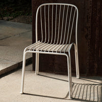 White metal chair with a minimalist design featuring sleek vertical lines and a grid-patterned seat.