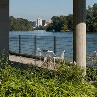 "Elegant white outdoor table set with greenery and water views, featuring subtle natural patterns and vibrant colors."