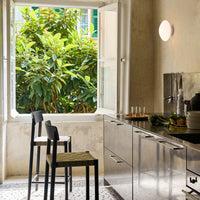 Stylish black and green bar stools with a sleek silver kitchen backdrop and natural greenery outside the window.