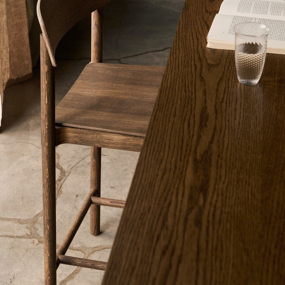 Brown wooden chair and table with a smooth, dark grain pattern, set against a textured concrete floor.