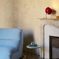Light blue sofa with subtle texture, paired with a striking red lamp and neutral-toned walls, creating a warm, inviting vibe.