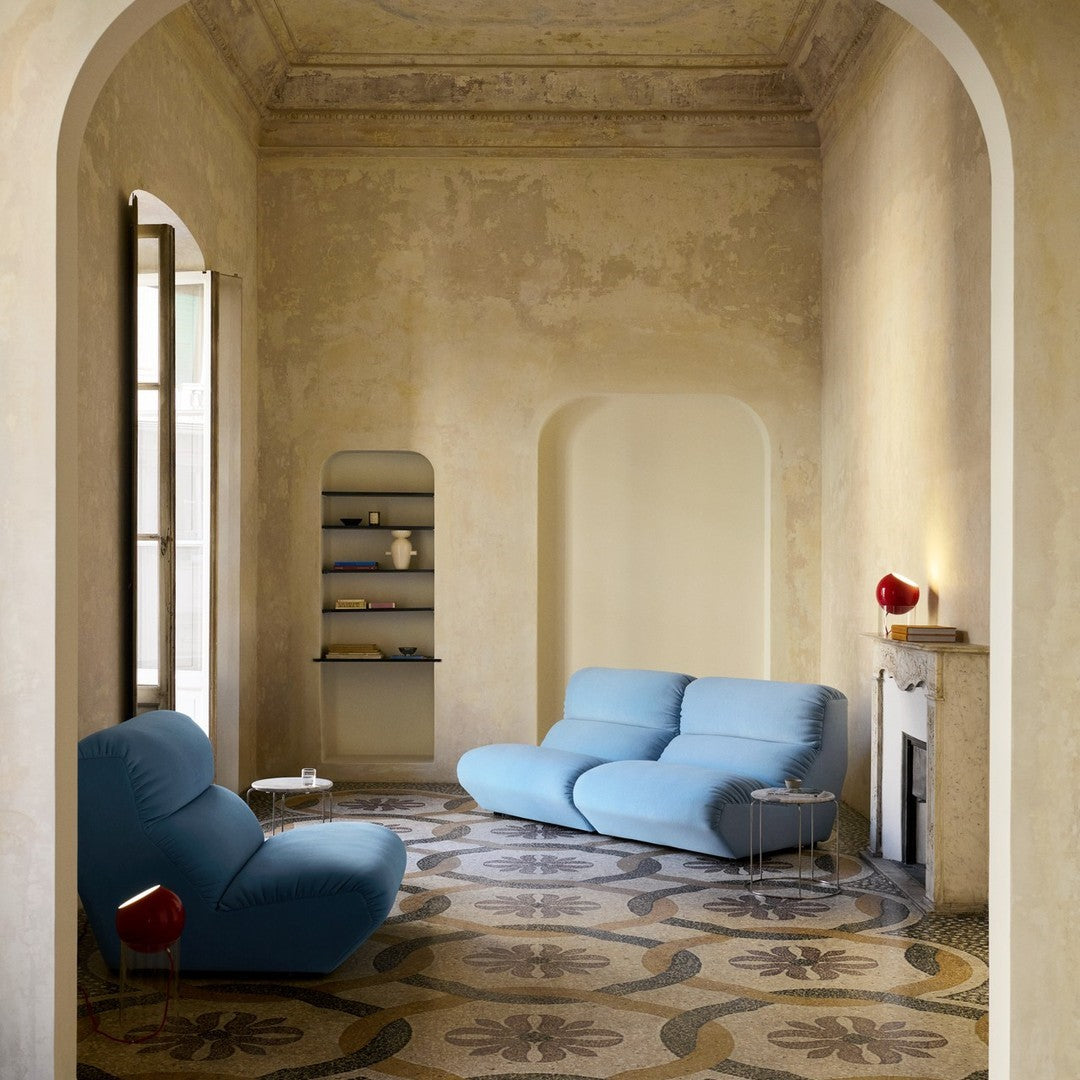Light blue sofas on a patterned floor with earthy tones and subtle floral designs in a minimalist room.
