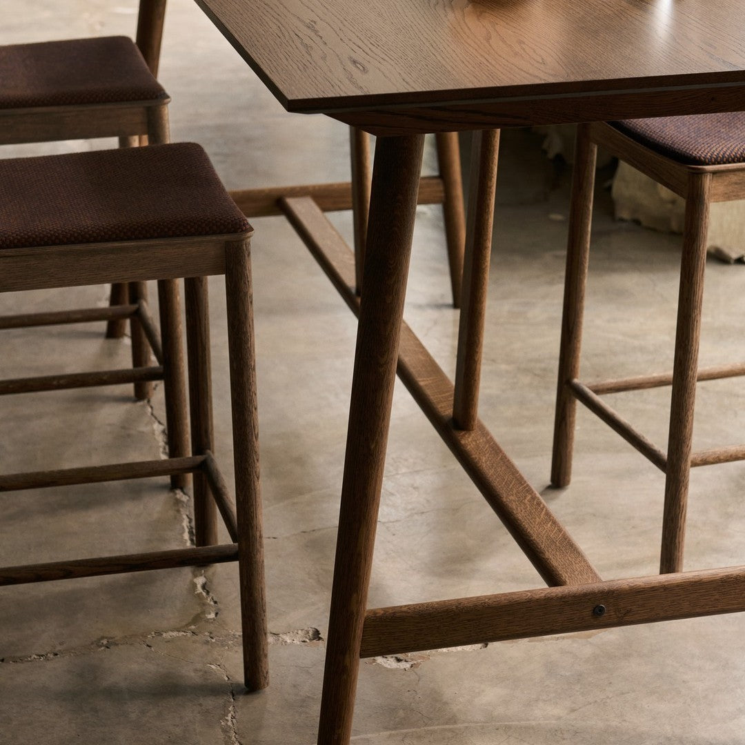 Brown wooden table and chairs with textured brown upholstery on a neutral concrete floor. Elegant and modern design.