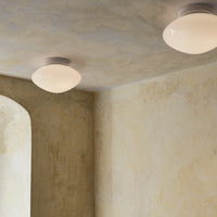 Soft white ceiling light against a textured beige wall with subtle gray and yellow hues.
