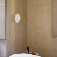 "Soft white lamp against a textured beige wall, adding subtle elegance to the warm-toned interior."
