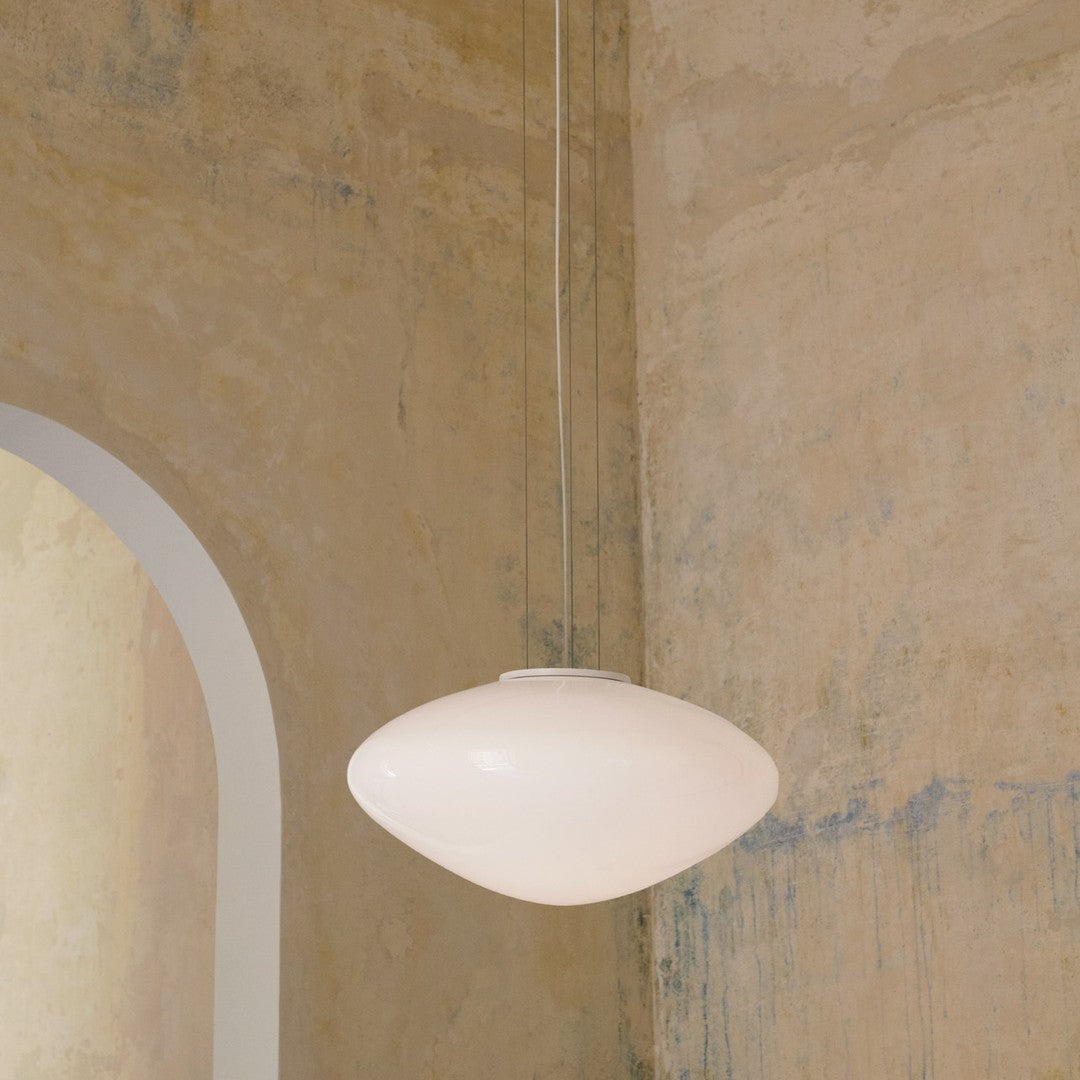 Sleek white pendant lamp hanging against a textured, muted beige and blue wall. Elegant and modern design.
