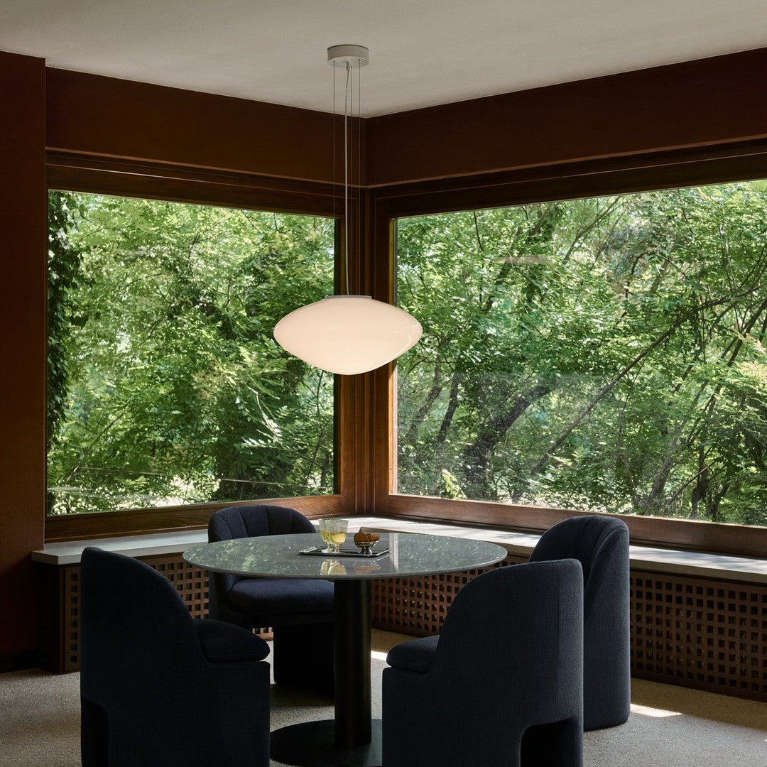 Modern pendant light with a white, organic shape; deep navy chairs and warm wood accents create a cozy atmosphere.