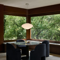 Modern pendant light with a white, organic shape; deep navy chairs and warm wood accents create a cozy atmosphere.