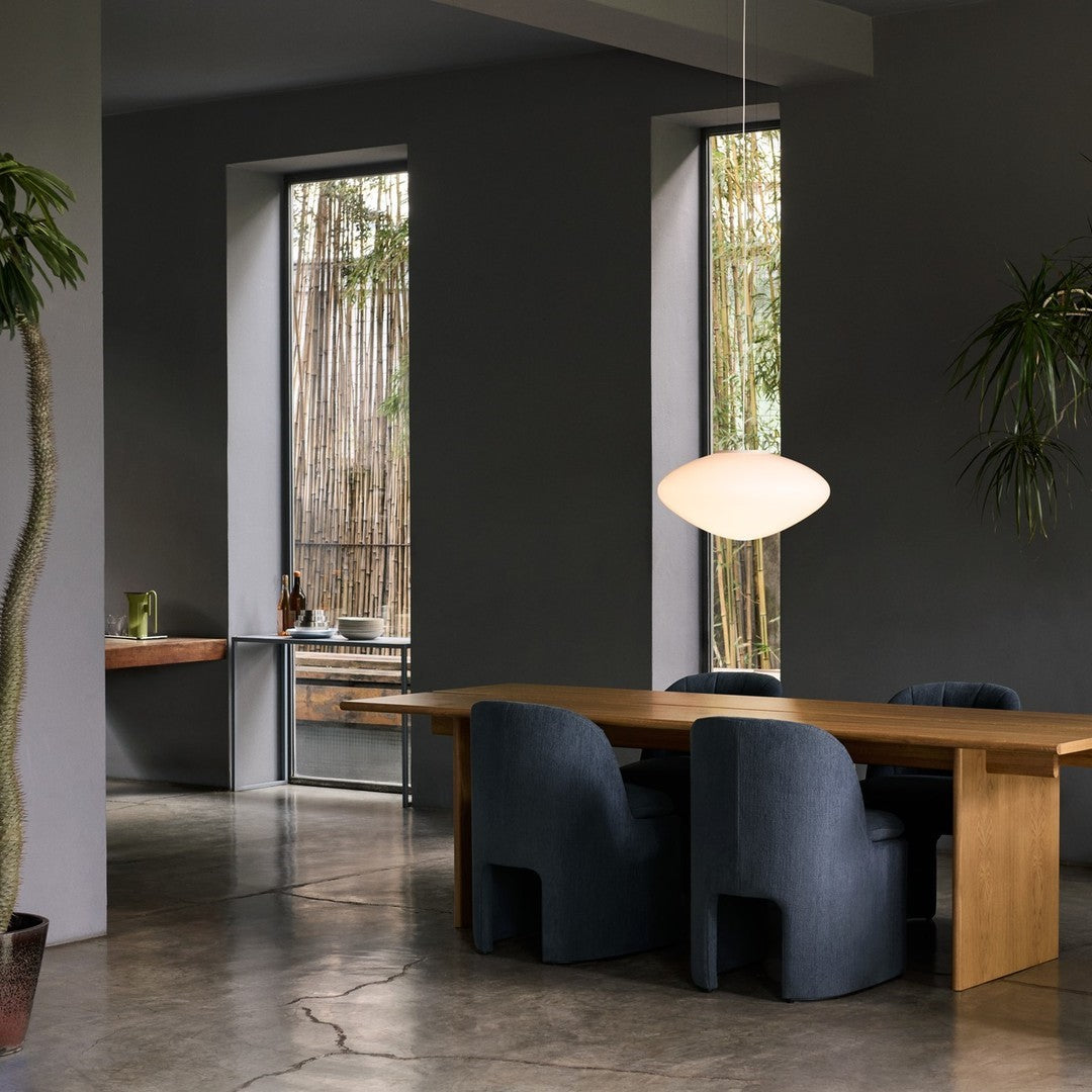 Stylish navy blue chairs and warm wooden table set against a soft gray wall and natural light from windows.