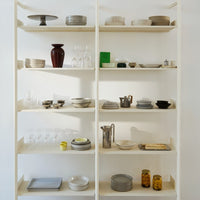 Neutral and vintage kitchenware featuring beige, white, dark brown, and green accents on open shelves.
