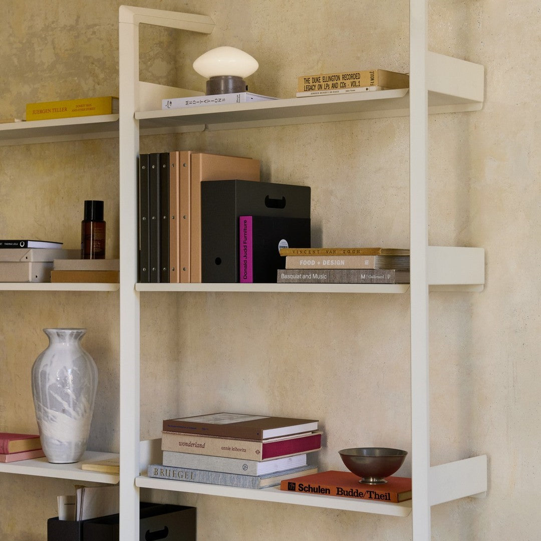 Stylish modern shelving unit featuring neutral tones, earthy textures, and geometric patterns in decorative items and books.