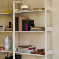 Stylish modern shelving unit featuring neutral tones, earthy textures, and geometric patterns in decorative items and books.