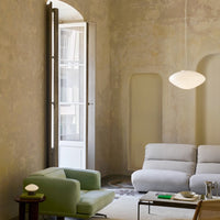 Stylish living room featuring soft green and gray furnishings against a muted beige wall with subtle textures.