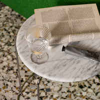 Marble tabletop, clear ribbed glass, silver tube, and patterned green and white floor tiles. Minimalist, modern colors.