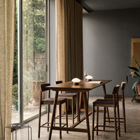 Modern dining area featuring earthy tones, warm beige curtains, and rich brown wooden furniture with subtle textured patterns.