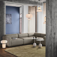 Modern living room with a beige sectional sofa, soft green rug, blue accent wall, and warm-toned lighting.