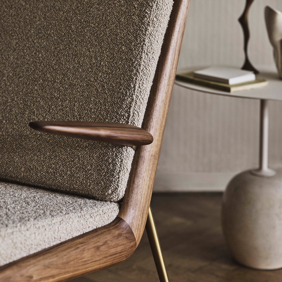 Beige textured upholstery with a warm wooden armrest, complemented by a modern neutral-toned side table.