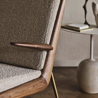Beige textured upholstery with a warm wooden armrest, complemented by a modern neutral-toned side table.