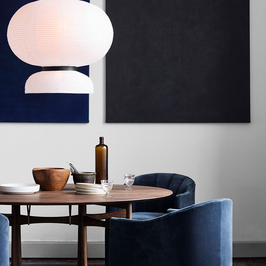 "Modern dining set featuring navy blue chairs, neutral walls, and geometric light fixtures."