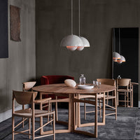 Modern dining room featuring a round wooden table, beige curtains, red velvet chair, and minimalist light fixtures.
