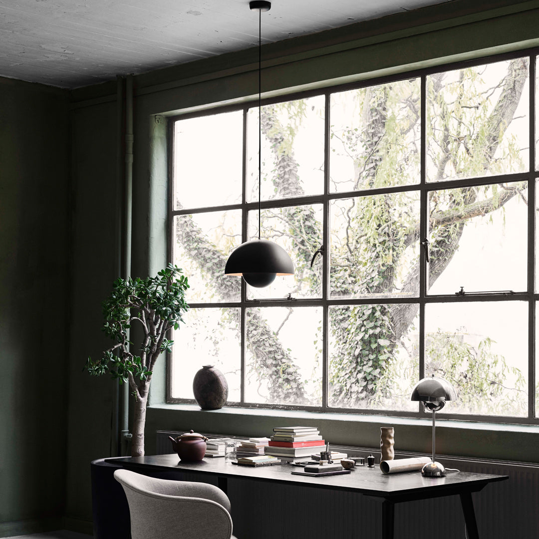 Stylish office scene featuring deep green walls, a minimalist black lamp, and soft beige accents. Nature-inspired patterns outside.