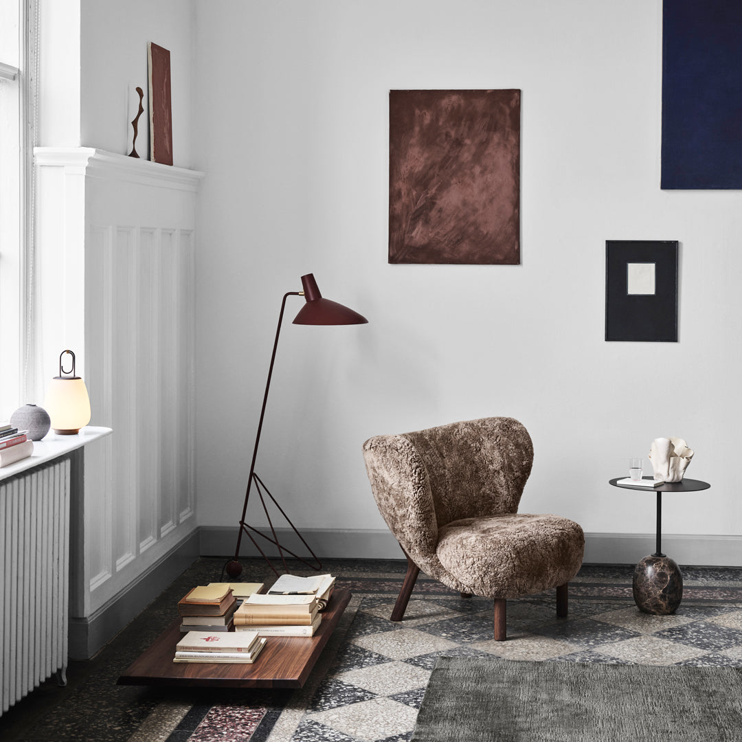 Cozy brown patterned chair in a minimalist room with gray, maroon, and navy blue accents on walls and decor.