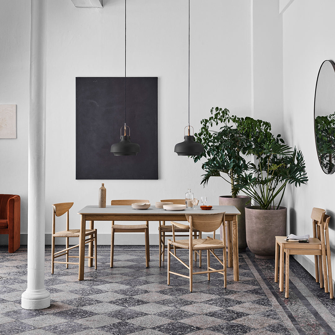 Modern dining room featuring earthy tones, geometric patterned flooring, and minimalist wooden furniture.