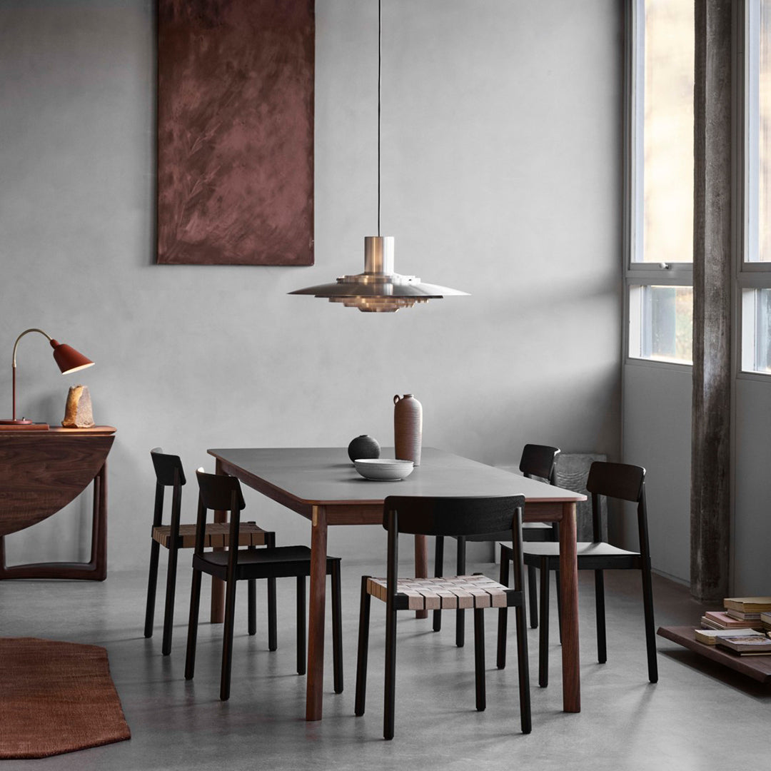Modern dining room featuring earthy tones, sleek black chairs, and a textured brown wall art piece.