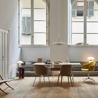 Modern workspace with neutral tones, wooden flooring, and pastel-colored furniture accents in a bright, airy room.