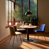 Modern dining set featuring beige, blue, and cream chairs around a round marble table in a sunlit room.
