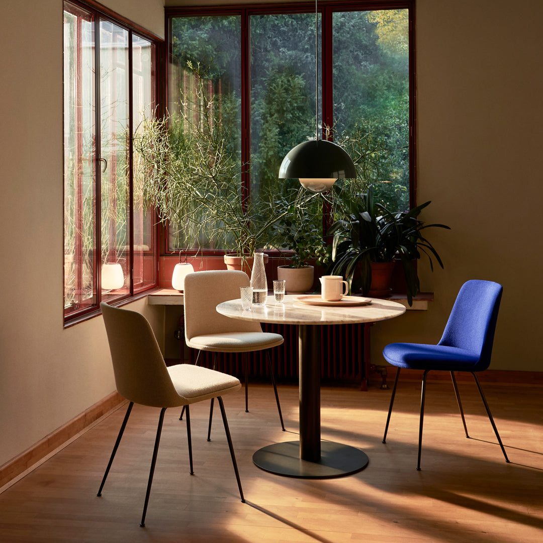 Elegant dining scene featuring beige, white, and blue chairs around a round white table, with natural light and greenery.