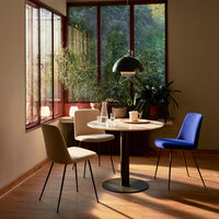 Elegant dining scene featuring beige, white, and blue chairs around a round white table, with natural light and greenery.