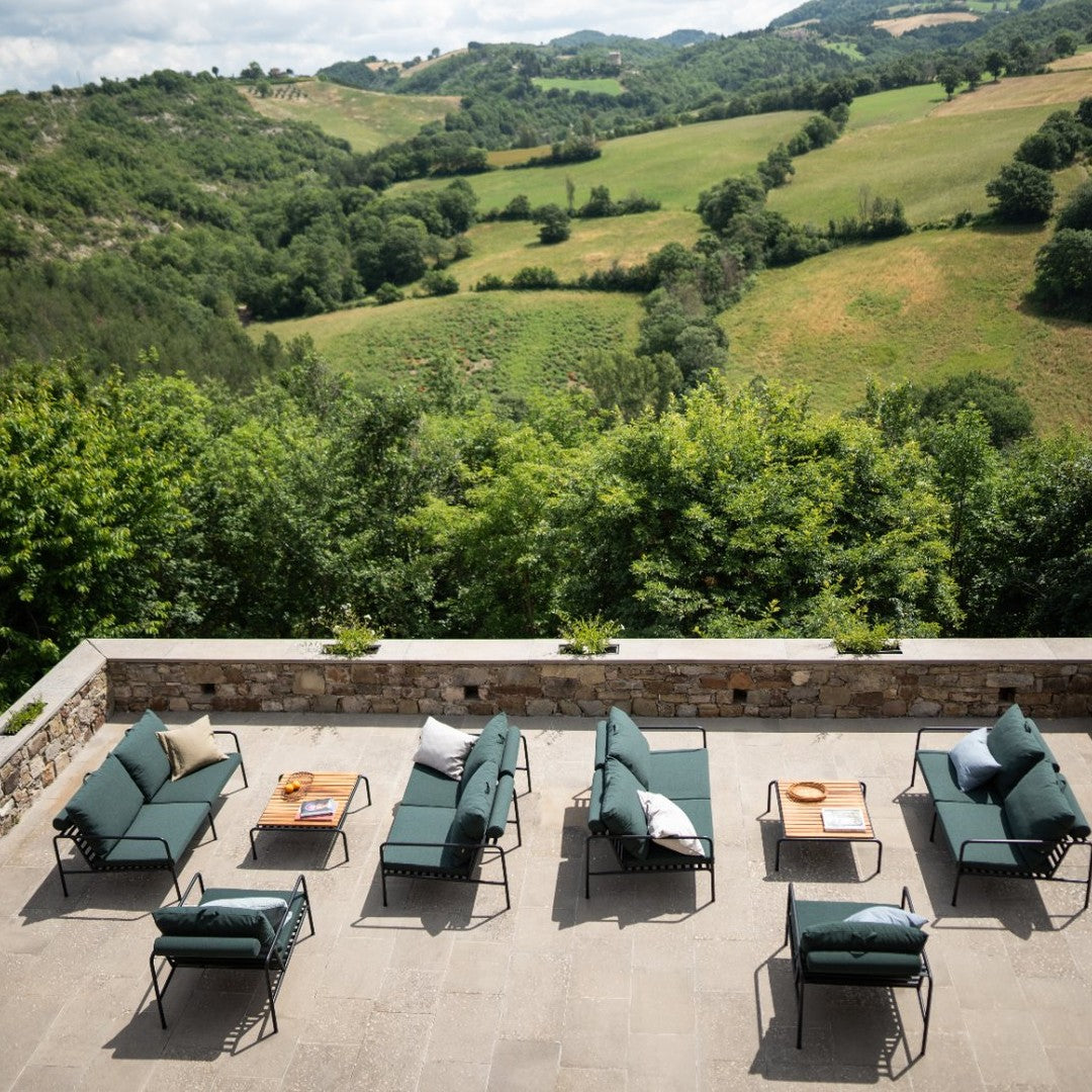 "Luxurious outdoor lounge chairs in deep green fabric and neutral cushions, set against a scenic nature backdrop."