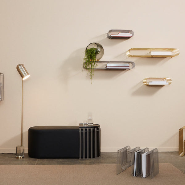 Black and gold modern furniture with sleek lines and reflective surfaces on a neutral wall backdrop.