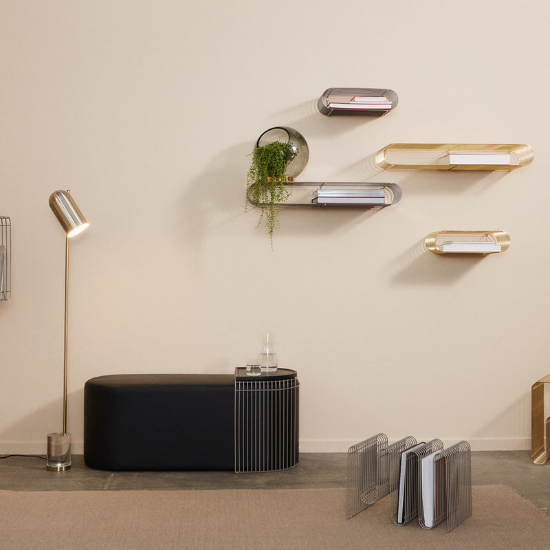 Black and gold modern furniture with sleek lines and reflective surfaces on a neutral wall backdrop.