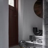 "Elegant gray vases with textured patterns, complemented by a dark red door and metallic wall art."
