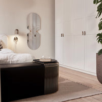 Elegant black and gold accent table in a serene beige and white bedroom, featuring modern minimalist decor and soft textures.