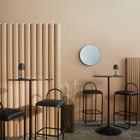 Contemporary cafe scene with beige walls, black furniture, and circular mirror, featuring vertical wooden paneling.