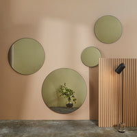 "Set of round mirrors with green-tinted reflections on a soft peach background and vertical wooden panel texture."