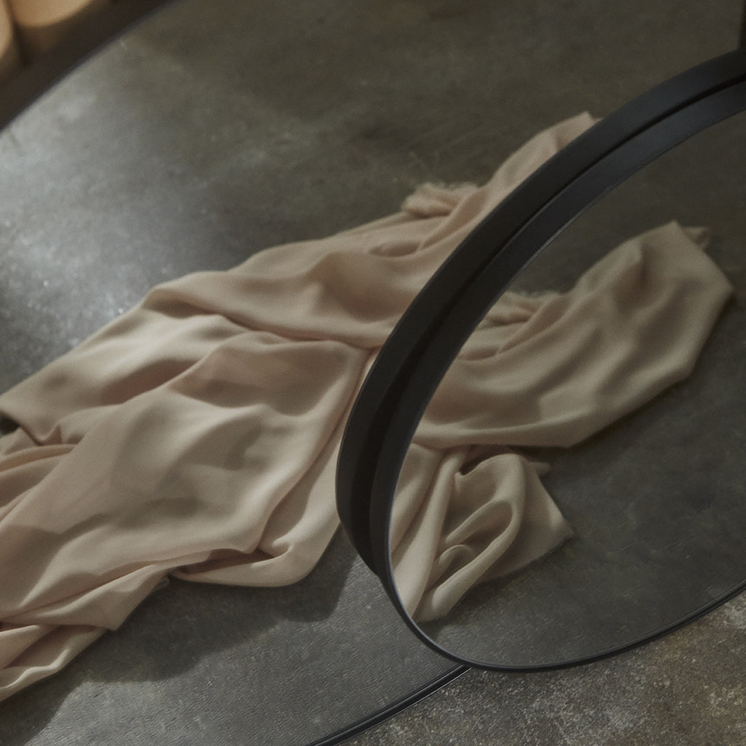 Beige satin fabric draped softly on a textured surface, reflecting light with subtle sheen and smooth flow.