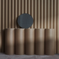Brown cylindrical paper tubes against a textured beige wall, with a round black mirror above.